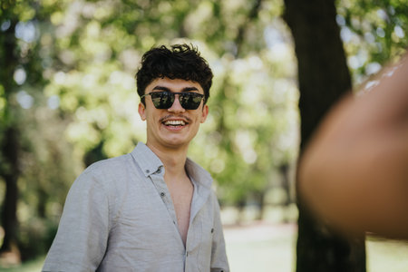 Young man smiling in the park on a sunny day, enjoying outdoor activitiesの写真素材