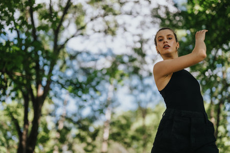 Lovely girl dancing in nature, female dancer performing modern dance outdoors surrounded by lush greeneryの写真素材
