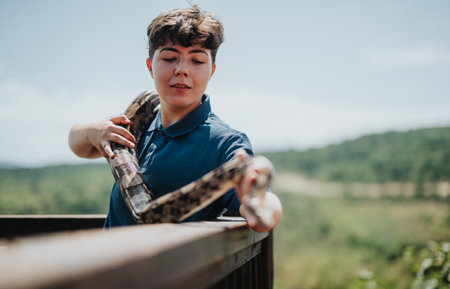 Girl enjoying playful moment with her pet snake on a sunny dayの写真素材