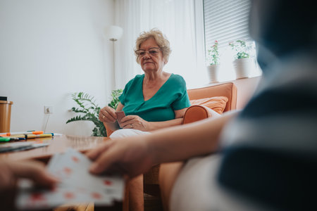 Senior woman enjoying a card game with family at homeの写真素材