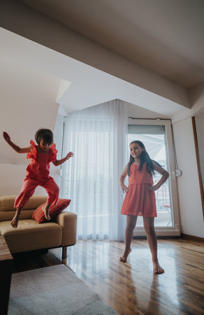 Joyful children playing energetically in the living room at homeの写真素材