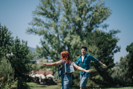Group of friends enjoying a playful moment by the fountain in a sunny parkの写真素材