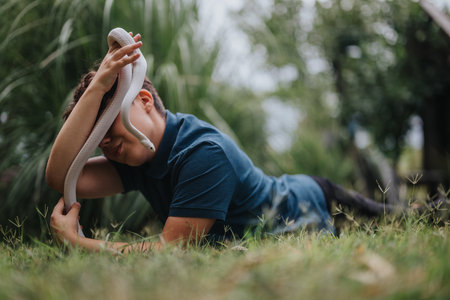 Young girl plays with a pet snake outdoors in nature settingの写真素材