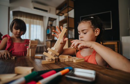 Two girls playing with wooden blocks in a cozy home settingの写真素材