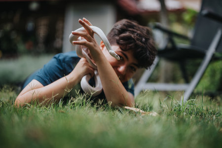 Young girl joyfully playing with a white snake in the gardenの写真素材