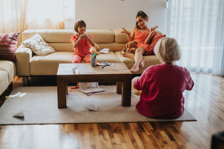 Children playing with paper airplanes in sunny living roomの写真素材