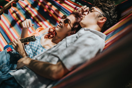 Young couple relaxing in a colorful hammock on a sunny day, smiling and enjoying each others companyの写真素材
