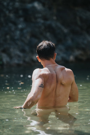 Man with tattoo swimming in natural water body on a sunny day