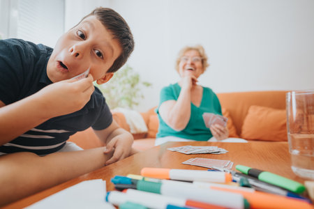 Grandmother and grandson playing cards and enjoying fun bonding timeの写真素材