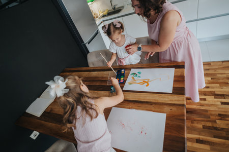 Mother painting with her daughters at home, enjoying a creative family activityの写真素材