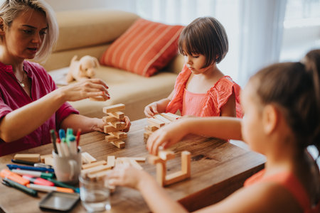Mother and daughters playing with blocks at homeの写真素材