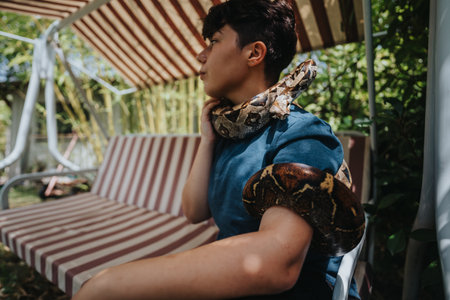 Young girl interacting with snakes in a sunny garden settingの写真素材