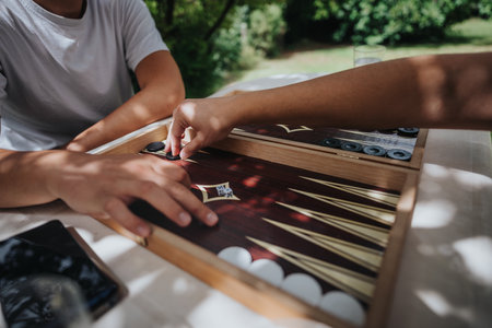 Two people playing backgammon outdoors on a sunny dayの写真素材