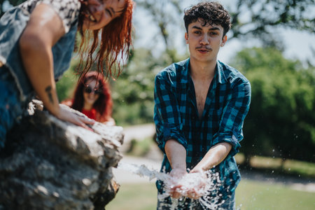 Friends having fun splashing water on a hot summer day outdoorsの写真素材