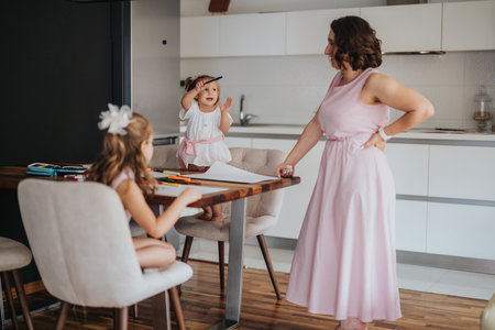 Young mother drawing and painting with her little daughters at homeの写真素材