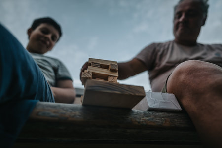 Father and son bonding over a wooden block game outdoorsの写真素材