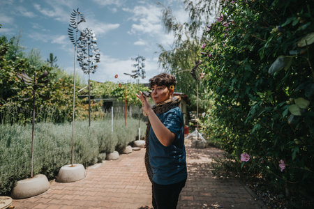 Young girl confidently interacting with a snake in a garden settingの写真素材