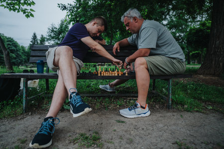 Two men playing chess on a park bench in a serene settingの写真素材