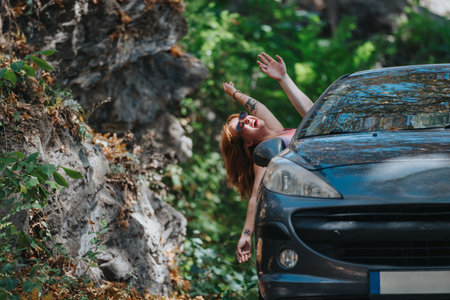 Joyful woman enjoying a road trip in a car through natureの写真素材