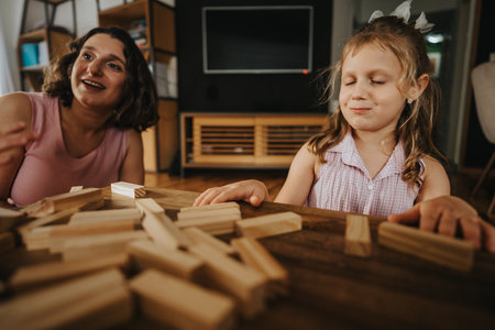 Mother playing with little daughter at home with wooden blocksの写真素材