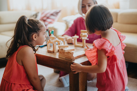 Children playing with wooden blocks in a cozy living roomの写真素材