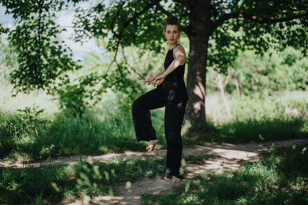 Girl performing modern dance in nature, exploring movement and expression in serene outdoor settingの写真素材