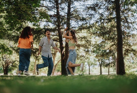 Young people having fun in the park, running in circles, laughing, and creating beautiful friendship memoriesの写真素材