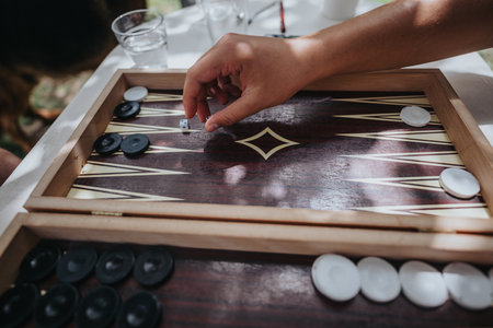 Hand playing backgammon in an outdoor setting with sunlightの写真素材