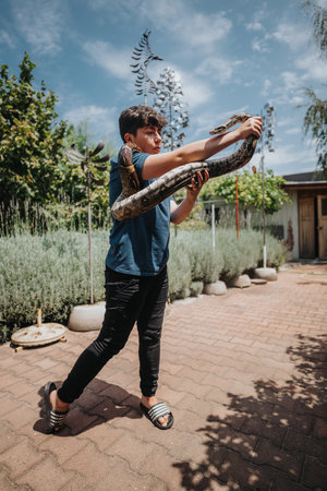 Young girl playing with pet snake in backyard garden