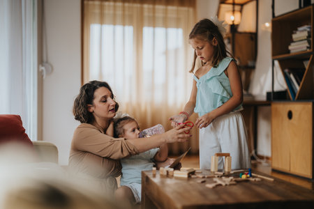 Mother and daughters enjoying creative playtime with educational toys at homeの写真素材