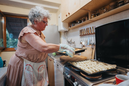 Senior woman baking pastries in a cozy home kitchen settingの写真素材