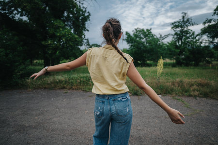 Young woman enjoying nature with arms outstretched in a serene outdoor settingの写真素材