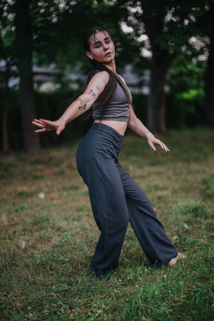 Woman dancing gracefully outdoors in nature-filled park settingの写真素材