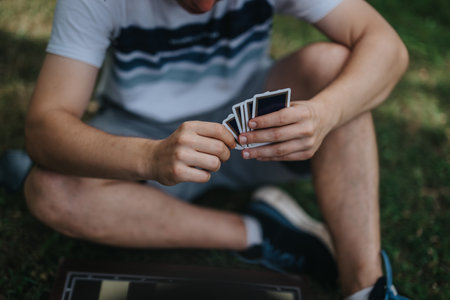 Person playing a game outdoors with focus on card handの写真素材