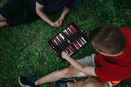 Two friends enjoying a game of backgammon on the grassの写真素材