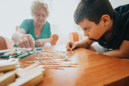 Grandmother and young boy playing pick-up sticks in cozy living room