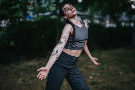 Young woman dancing freely in nature wearing a gray sports outfitの写真素材