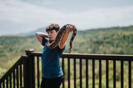 Young girl enjoying outdoor adventure with pet snake on a sunny dayの写真素材