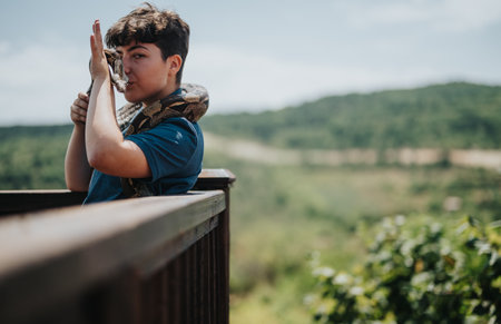 Young girl interacting with snake on a sunny outdoor deckの写真素材