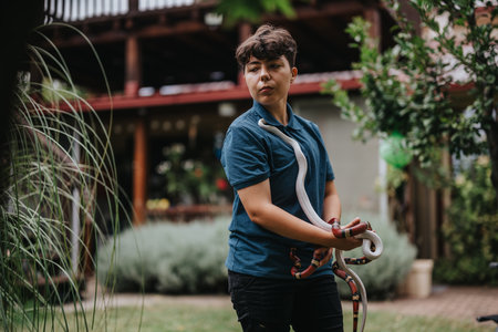 Girl engaging with colorful snakes in a lush garden settingの写真素材