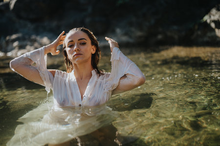 Woman in white dress enjoying nature in a serene river landscapeの写真素材