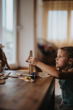 Young girl building a wooden tower at home with focus and creativityの写真素材