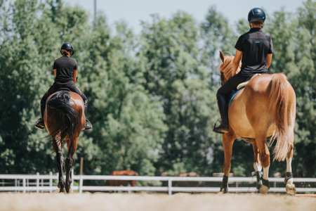Two people riding horses at an equestrian center during summerの写真素材