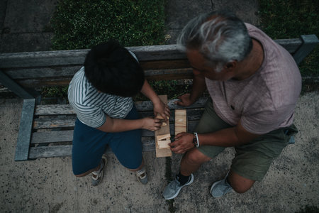 Grandfather and grandson bonding over a wooden game outdoorsの写真素材