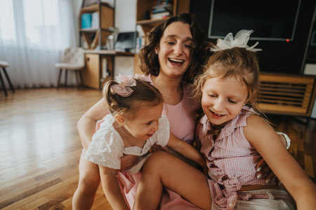 Happy mother spending quality time with her young daughters in a cozy home environmentの写真素材