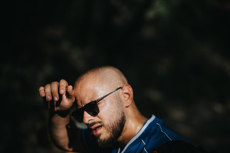 Tired athlete wiping sweat after intense workout in the outdoorsの写真素材