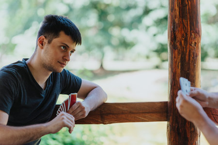 Young man playing cards outdoors in a natural settingの写真素材