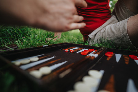 Friends playing backgammon outdoors on a sunny day in the parkの写真素材