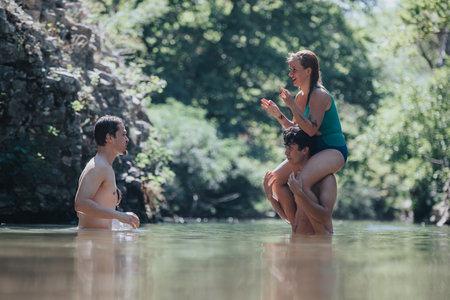 Friends enjoying playful swim in a scenic natural river settingの写真素材