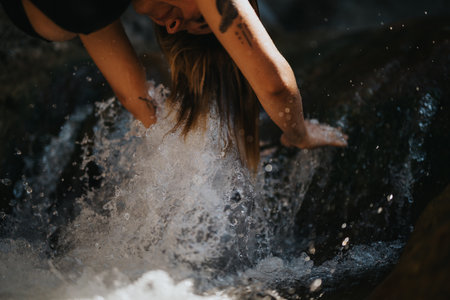 Person cooling off in a river at the mountain, refreshing and adventurous outdoor activityの写真素材